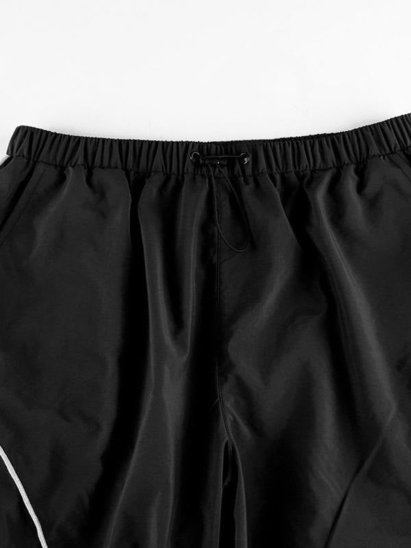 Pantalones de paracaídas negros con bolsillos cargo y detalle de ribete